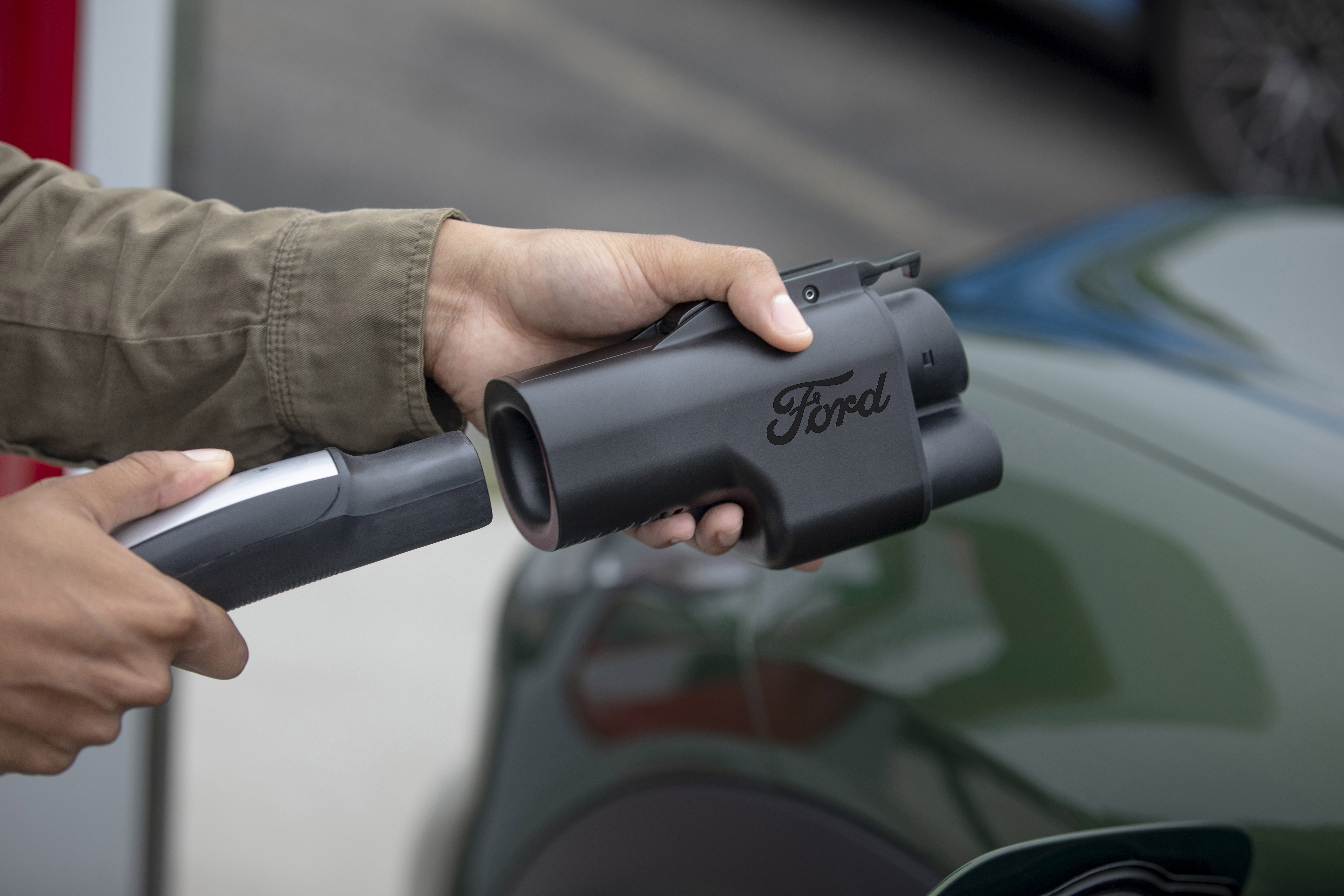 Someone places a Ford charging adapter on the charger cable.